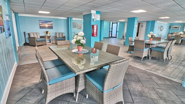 A spacious indoor area with wicker furniture, a glass table, and a blue wall.