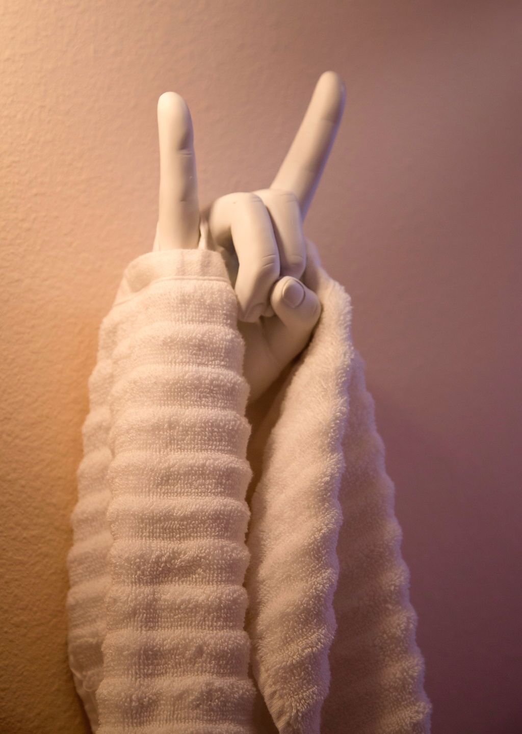 A mannequin with a white sweater making a peace sign.