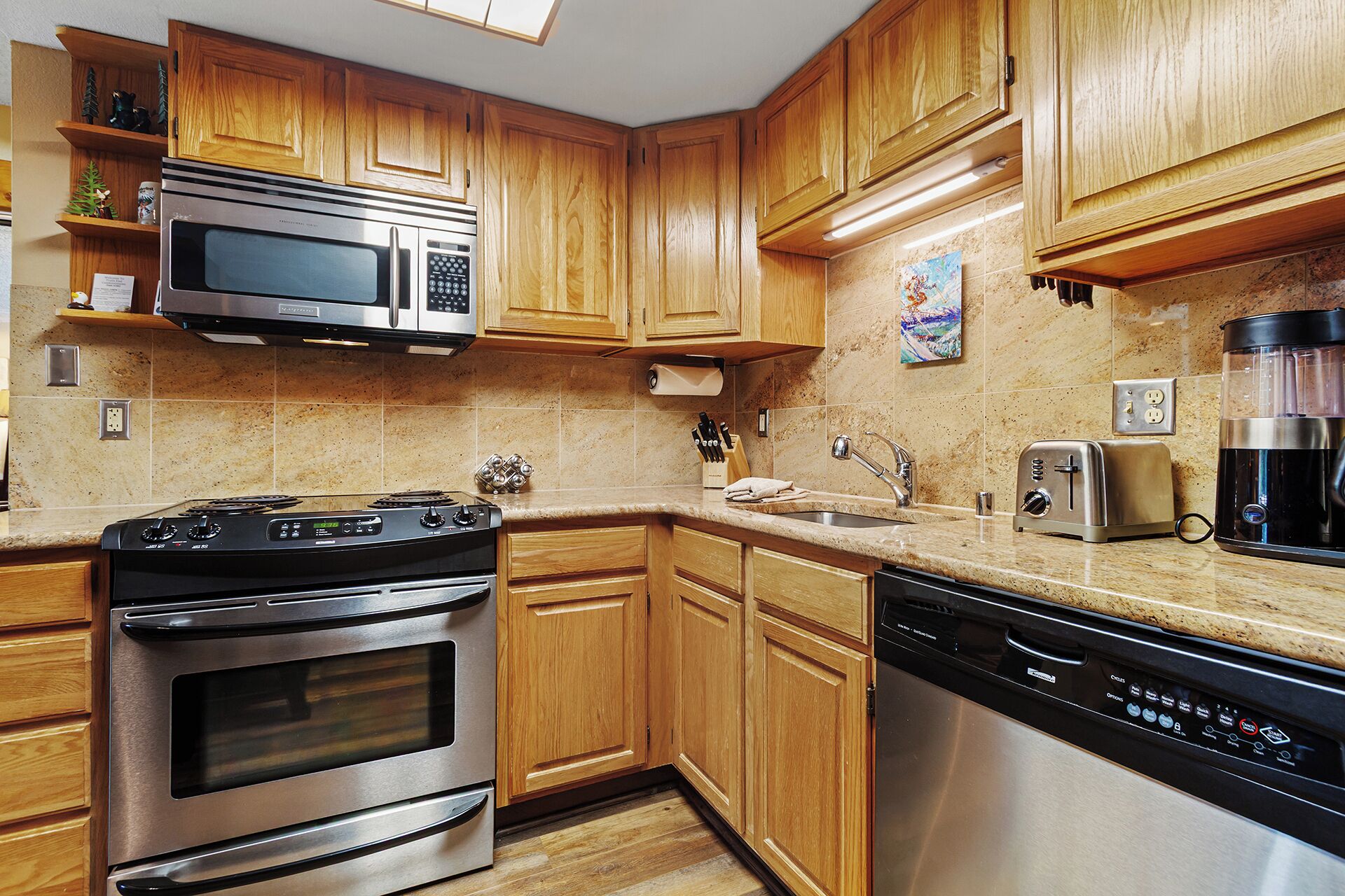 A modern kitchen with wooden cabinets, stainless steel appliances, and a granite countertop.