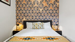 Ein Hotelzimmer mit einem Bett, einer Wand mit Muster und zwei Nachttischlampen.