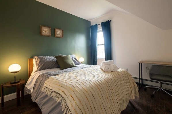 A bedroom with a bed, bedside tables, a chair, and a window with curtains.