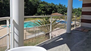 A balcony with a view of a swimming pool and lush greenery. - Appartement à la mer (Soulac-sur-Mer)