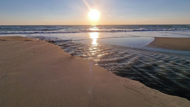 A beach with a clear sky and the sun setting over the ocean. - Appartement à la mer (Soulac-sur-Mer)