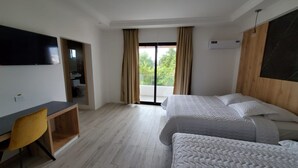 A hotel room with a bed, a desk, a chair, a TV, and a balcony with curtains. - Grand Hotel Leon Marino Galapagos (Puerto Ayora)