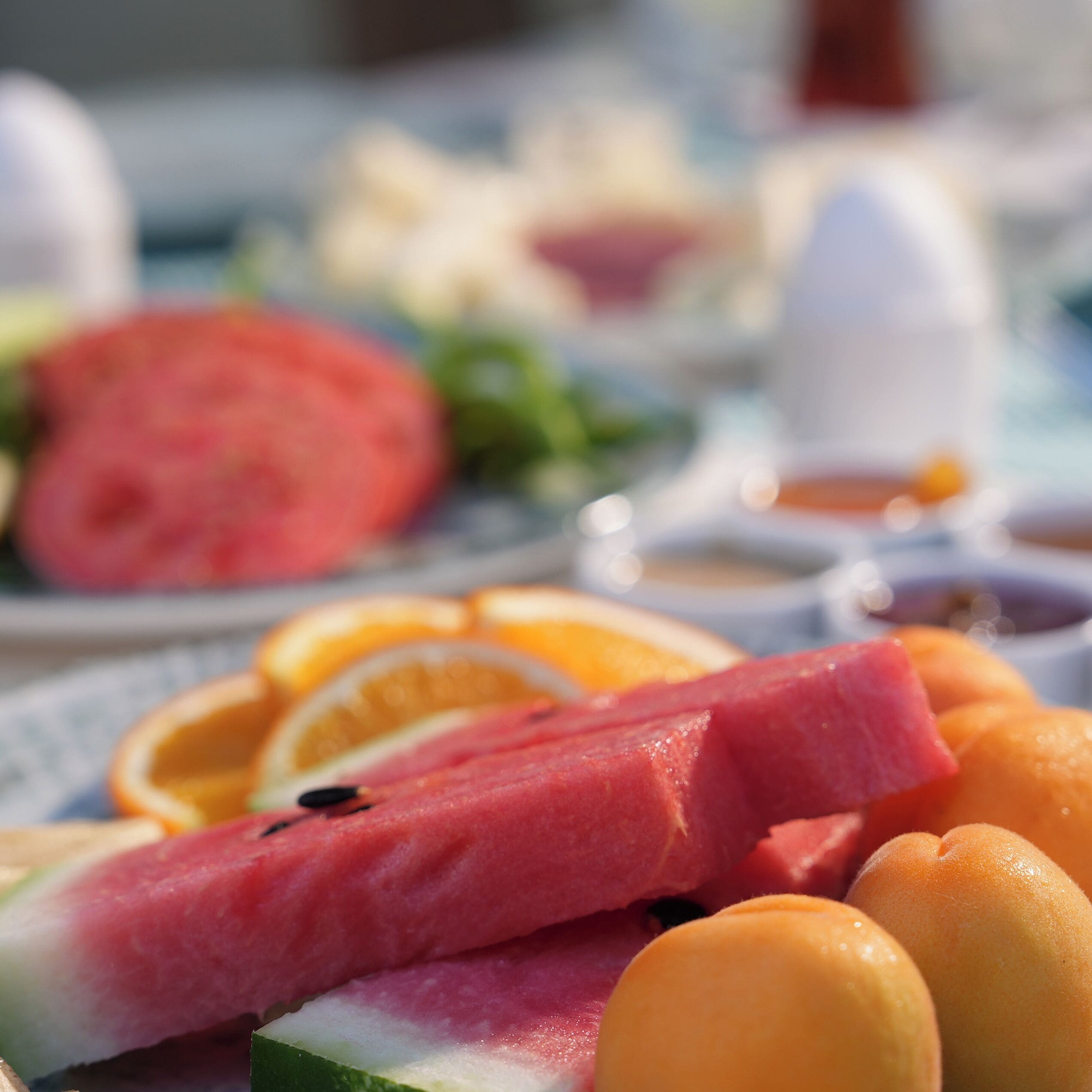 A close-up of a fruit platter with watermelon, oranges, and a slice of watermelon on a table.
