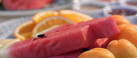 A close-up of a fruit platter with watermelon, oranges, and a slice of watermelon on a table.