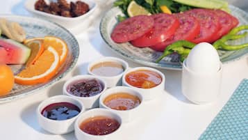 Une table sur laquelle on trouve divers aliments, notamment du pain, des tomates, des olives et des fruits.