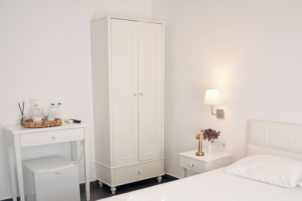Una camera d'albergo con un letto, un armadio, un comodino e una scrivania.