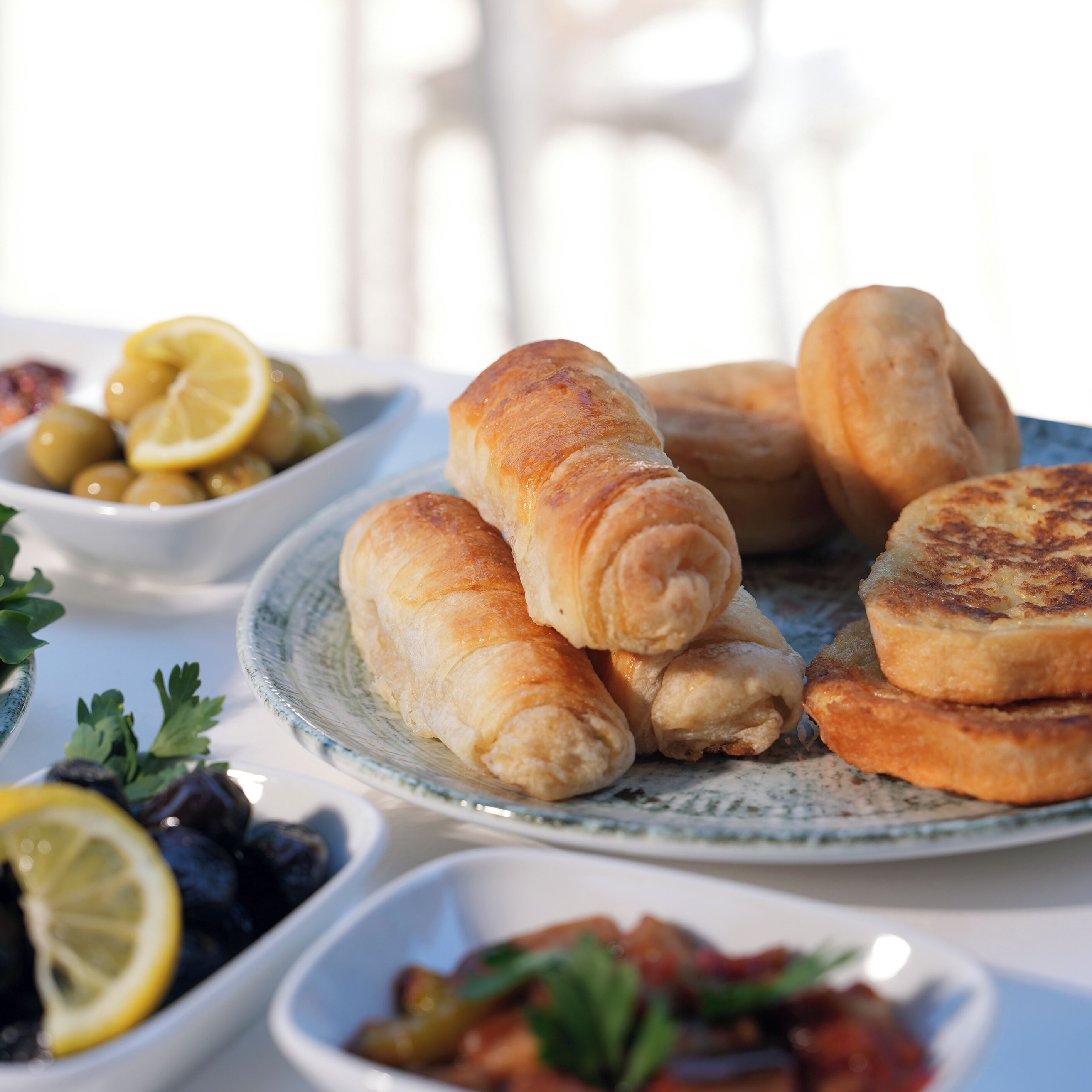 Un plato de croissants y un bol de aceitunas sobre una mesa.