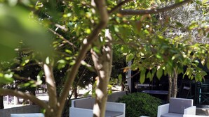 An outdoor seating area with white wicker furniture and a small table. - NİLİA BOZCAADA (Bozcaada)