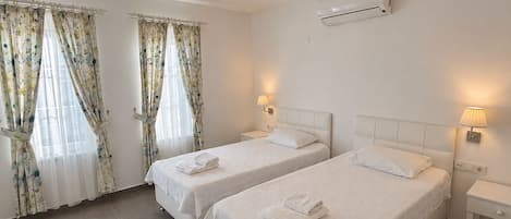 Habitación de hotel con dos camas, una lámpara de techo, un aire acondicionado y cortinas.