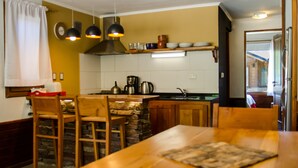 Una cucina con mobili in legno, una parete decorata con pietra e illuminazione a sospensione.