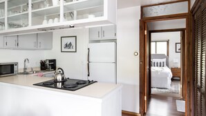 A modern kitchen with white cabinetry, a built-in stove, and a microwave. There is a refrigerator and a sink with a faucet. A framed picture hangs on the wall above the sink. - Outpost: Spruces 10 - Located in the Aspens! (Wilson)