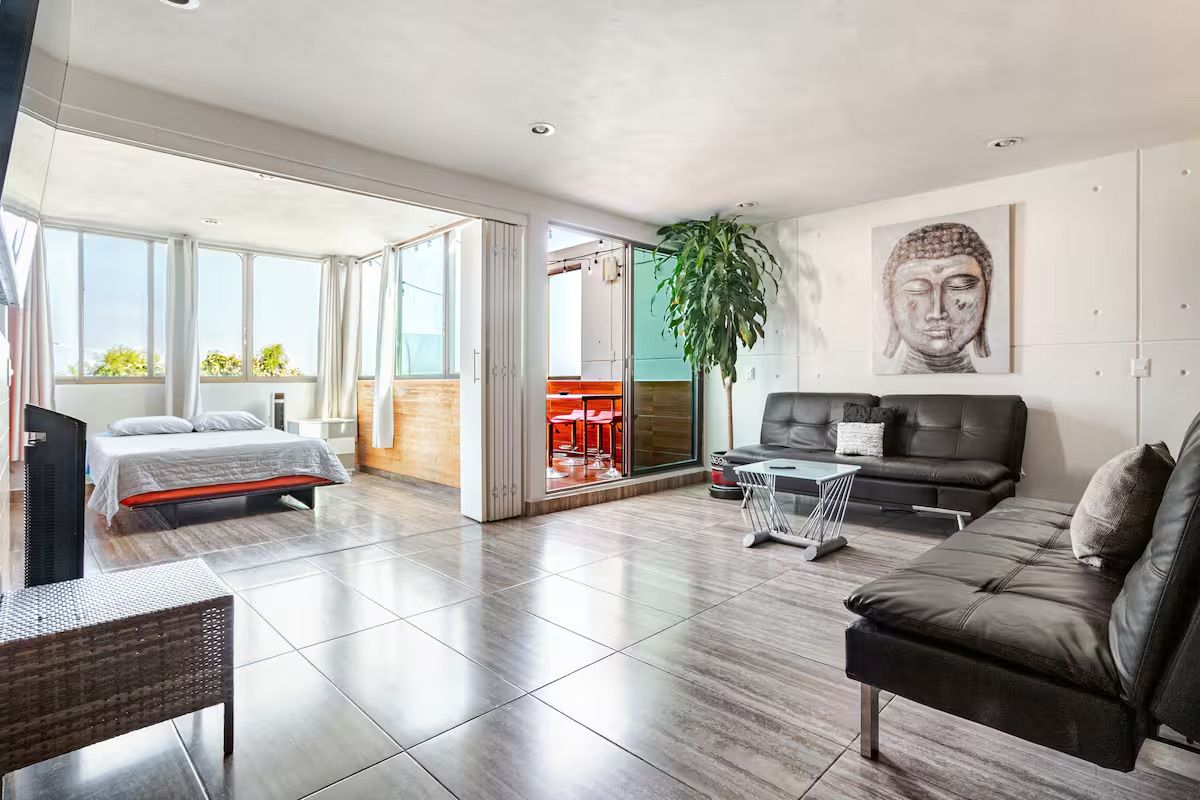 Un salon moderne avec un canapé, un lit et une grande fenêtre.