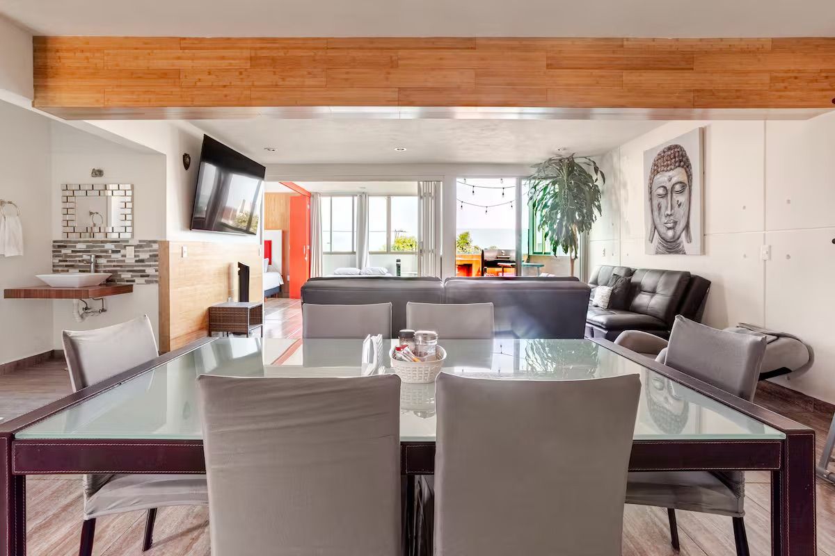 Un salon moderne avec une table à manger en verre, des canapés en cuir et une grande statue de Bouddha.