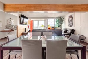 A modern living room with a glass dining table, leather sofas, and a large Buddha statue.