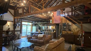 A spacious living area with a high wooden ceiling, a dining area with a table and chairs, and a kitchen visible through an open doorway. - One of a kind cozy Renovated VT Barn- where Family, Friends, Couples gather  (Shaftsbury)