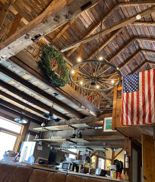 Un interior rústico con vigas de madera a la vista, una lámpara colgante y una bandera estadounidense.