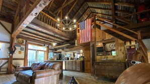 A rustic cabin interior with a cozy living area, a kitchen, and a loft bedroom. - One of a kind cozy Renovated VT Barn- where Family, Friends, Couples gather  (Shaftsbury)