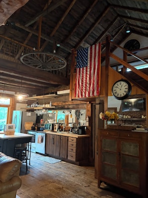 Eine rustikale Küche mit Holzbalken, einer großen amerikanischen Flagge, einer Uhr und einem alten Kühlschrank.