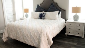 A neatly made bed with a white bedspread and two pillows, flanked by nightstands with lamps.