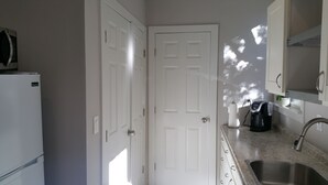 A compact kitchen with white cabinetry, a built-in microwave, a coffee maker, and a sink. - Remodeled Cottage in Trendy Berkeley/Oakland Rockridge Area (Oakland)