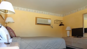 Et hotelværelse med seng, sengeborde, lamper, et kommode og et spejl.