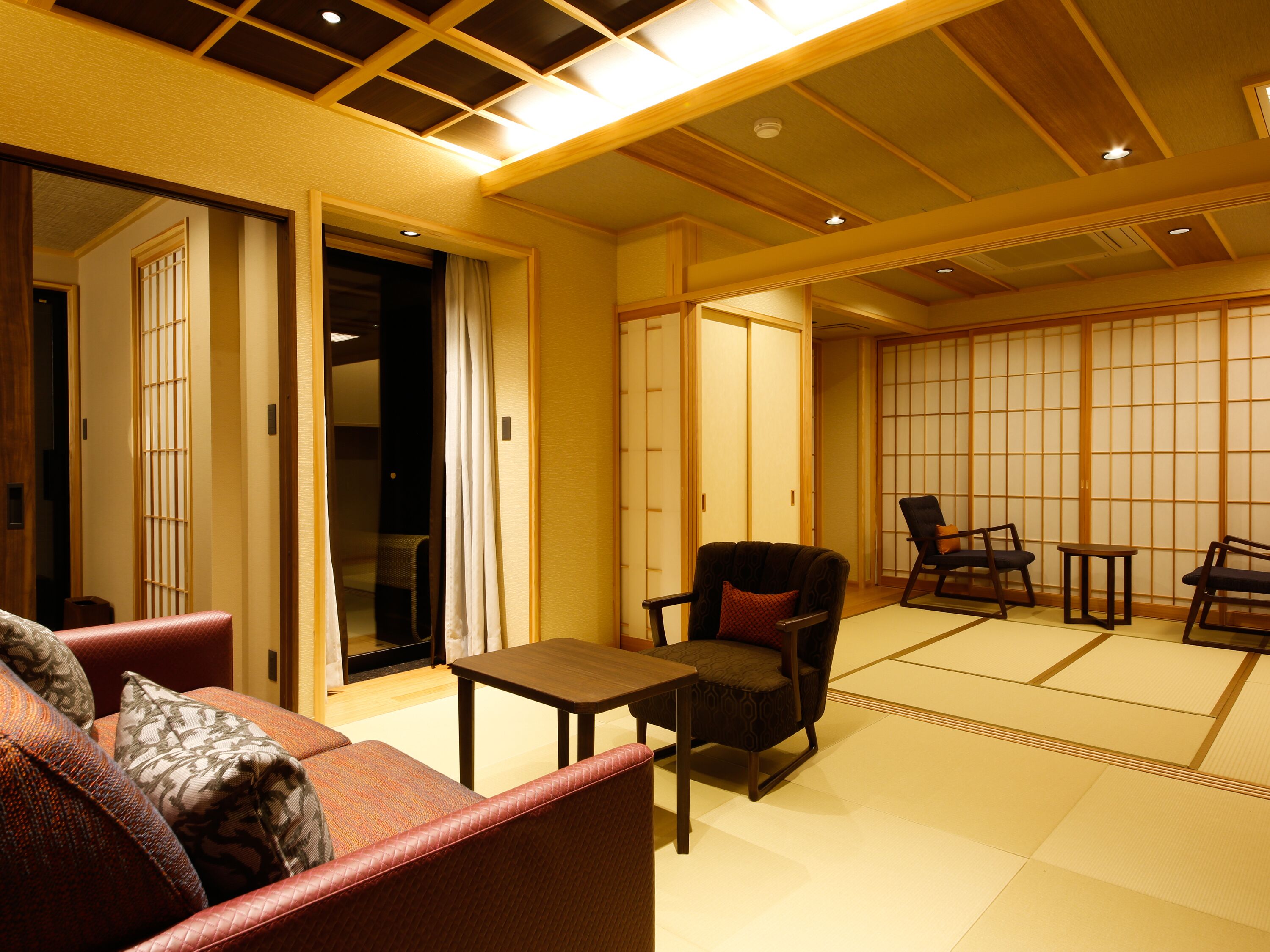 A traditional Japanese-style room with tatami flooring, a low table, and seating arrangements.