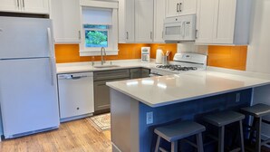 A modern kitchen with white cabinetry, a built-in microwave, a gas stove, and a large island with bar stools.
