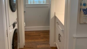 A laundry room with a washing machine, dryer, and a window with a view of greenery.