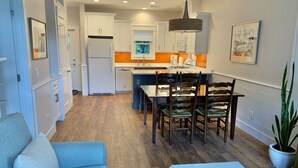 A modern kitchen with white cabinets, a built-in oven, and a dining area with a table and chairs.