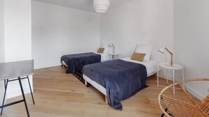 Une chambre à coucher au style minimaliste, avec deux lits, une petite table et une chaise.