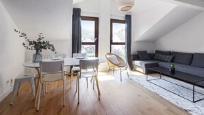 Un appartement moderne de style « loft », comprenant un coin repas, un canapé et une grande fenêtre laissant entrer la lumière naturelle.