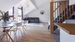 Un appartement moderne de style « loft », comprenant un coin repas, un canapé et un escalier.
