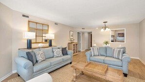 A living room with two light blue sofas, a wooden coffee table, and a patterned rug. - Newly furnished, Community Pool, Steps to Pier! (Saint Simons Island)