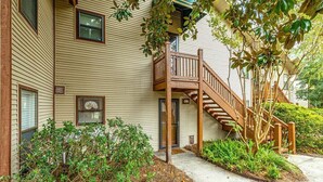 A two-story building with a wooden staircase leading to a balcony. - Newly furnished, Community Pool, Steps to Pier! (Saint Simons Island)