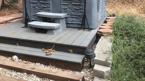 A hot tub with a stone facade, a wooden deck, and a picnic table. - Charming home in Sierra Nevada Foothills (Foresthill)
