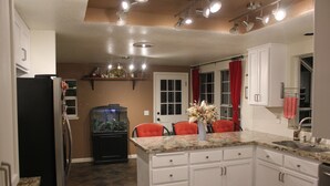 A kitchen with white cabinets, a black refrigerator, a fish tank, and a red curtain. - Charming home in Sierra Nevada Foothills (Foresthill)