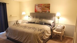 A bedroom with a large bed, two bedside lamps, a chair, and a painting on the wall. - Charming home in Sierra Nevada Foothills (Foresthill)
