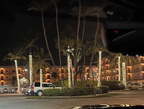 A hotel with multiple floors, palm trees, and a parking area with cars. - Beautiful Relaxing, Waterside Views! Walking Distance, Elevator,Garage, Pool&Spa (Naples)