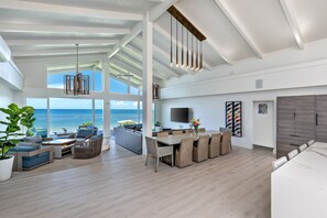Relax in a spacious living area with ocean views, a dining table, comfortable seating, and a flat-screen TV.