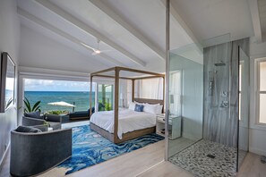 Relax in a spacious bedroom with a large bed, walk-in shower, and ocean views.