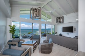 Relax in this stylish living area with a sofa, coffee table, and wicker chair, offering a view of the ocean.