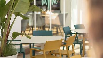 Un espacio interior moderno con suelo de madera, sillas amarillas y una planta grande en maceta.