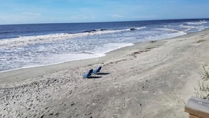Una playa con dos sillas azules de playa y una estructura de concreto a la derecha.
