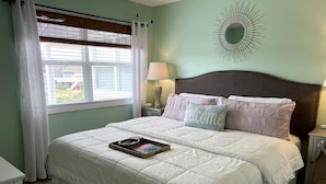 Una cama bien hecha con una colcha blanca y una almohada con la palabra 'welcome'.