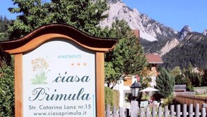 Et skilt for 'Ciasa Primula Apartments' med et bjerg i baggrunden.