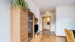 A modern apartment with a wooden wardrobe, a TV, and a dining area.
