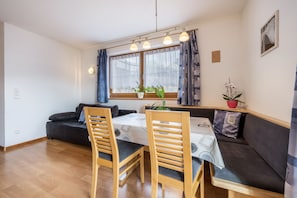 En matplats med ett bord, stolar, en soffa och ett fönster med gardiner.