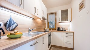 A modern kitchen with a sink, stove, and a bowl of fruit on the counter.